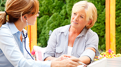 Home Health nurse taking blood pressure reading from a patient.